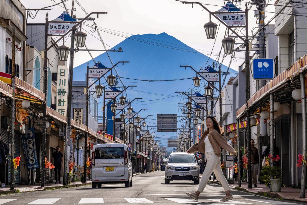 A woman crosses a street in Fujiyoshida, around 95km outside Tokyo, with Mount Fuji in the background. Photo: AFP