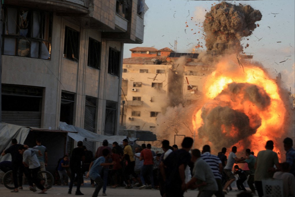 Palestinians react, as smoke and flames rise while a residential building collapses after an Israeli air strike in Gaza City on Sunday. Photo: Reuters