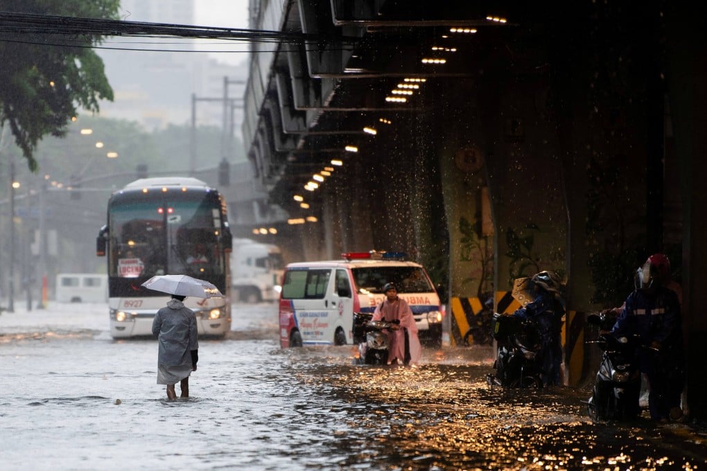 Pedestrians wade through a flooded street caused by heavy rains in Manila in July. Photo: AFP