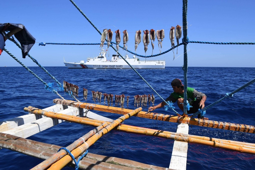 A Filipino fisherman dries squid on a fishing boat in the South China Sea with a Chinese coastguard ship in the background. Photo: AFP