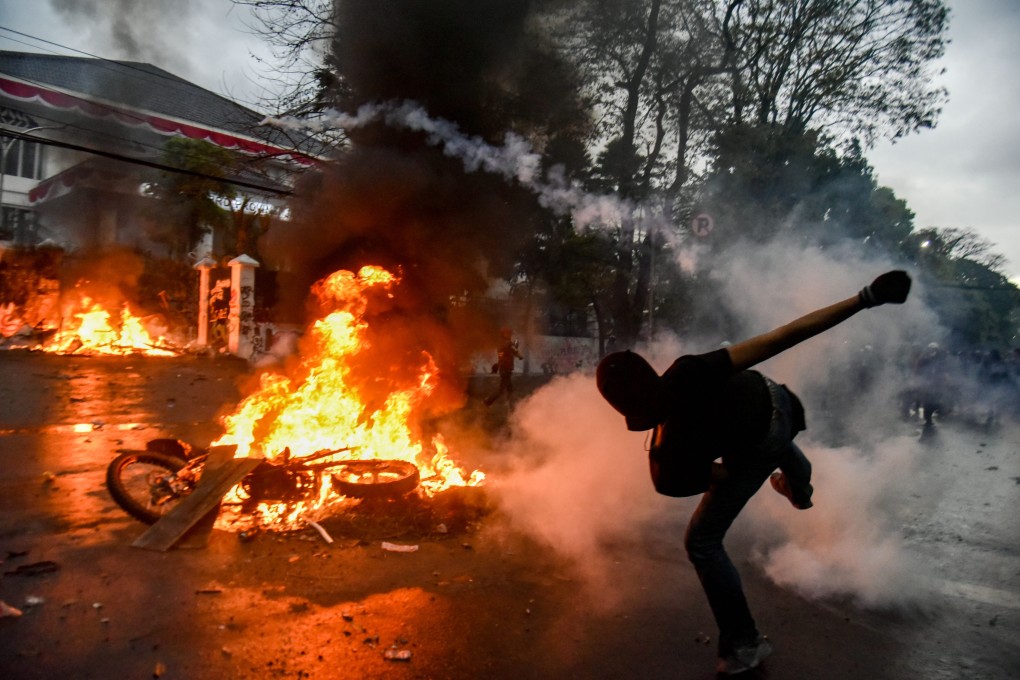 A protester throws back a tear gas canister during a clash with the police in Bandung last month over the death of a delivery rider who was run over by a police car. Photo: dpa
