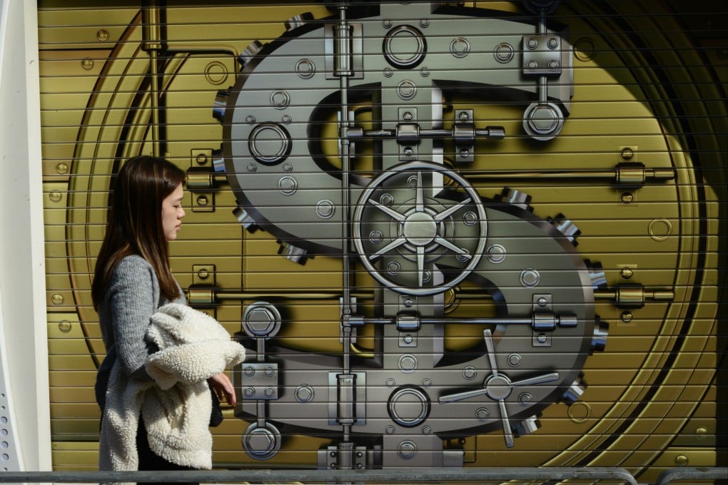 A woman walks past a currency mural on shop shutters in Hong Kong on December 26. Photo: Antony Dickson