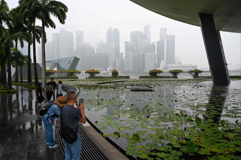People look at Singapore’s skyline shrouded under rain clouds on September 11. Photo: AFP