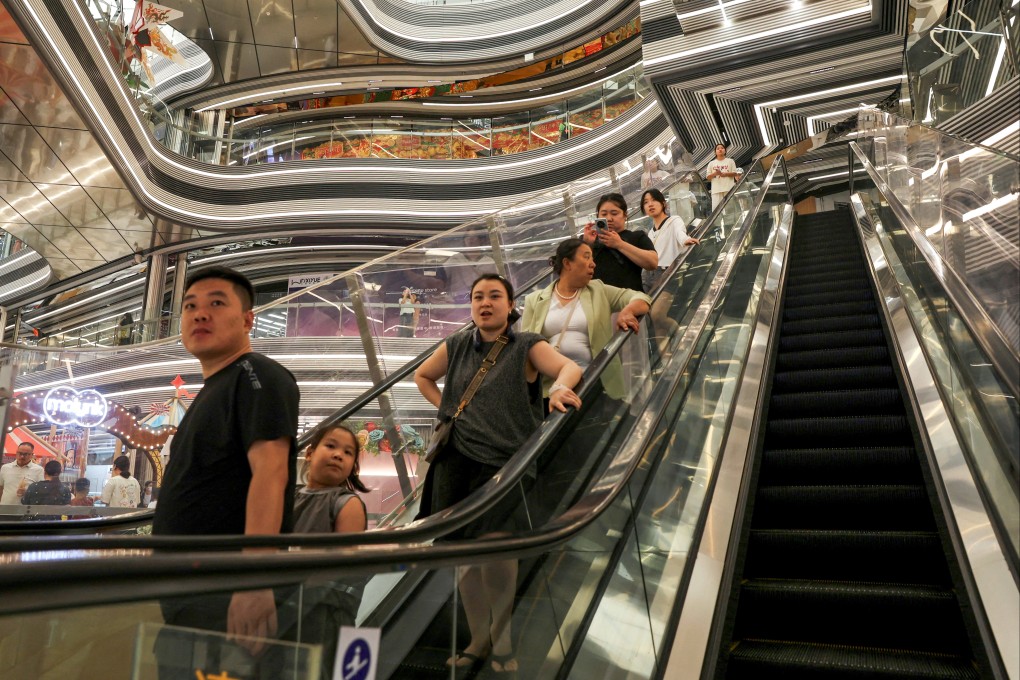 People ride an escalator at a shopping mall in Beijing, on July 31. Photo: Reuters