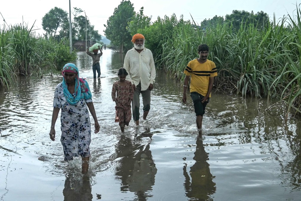 Villagers wade through floodwater near Punjab’s Amritsar on September 8. Floods and landslides are common during the monsoon season but experts say climate change is increasing their frequency, severity and impact. Photo: AFP