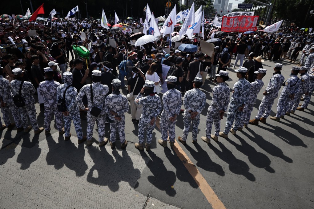 Coastguard personnel stand guard as protesters march during an anti-corruption rally in Manila on Sunday. Photo: EPA