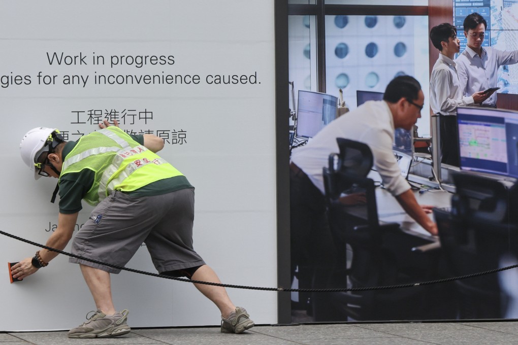 A worker smooths down a poster outside Jardine House in Central. City leader John Lee has stressed the need for flexibility in the labour import scheme. Photo: Jelly Tse