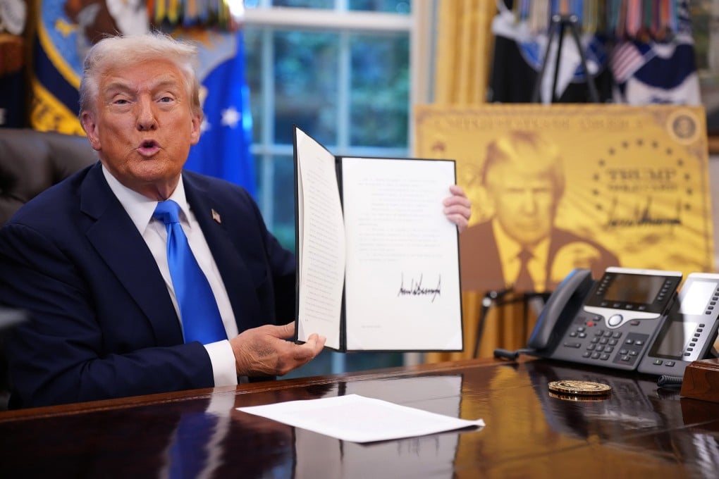 US President Donald Trump holds up an executive order establishing the “Trump Gold Card” in the Oval Office of the White House in Washington on September 19. Trump signed a series of orders establishing the Trump Gold Card€ and introducing a US$100,000 fee for H-1B visas. Photo: Getty Images