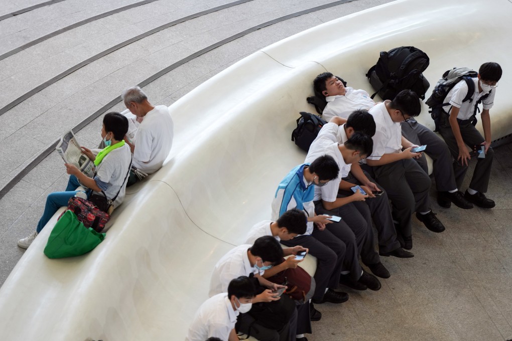 Students look at their phones as seniors read newspapers, at the Xiqu Centre in Tsim Sha Tsui on October 14, 2024. Photo: Eugene Lee