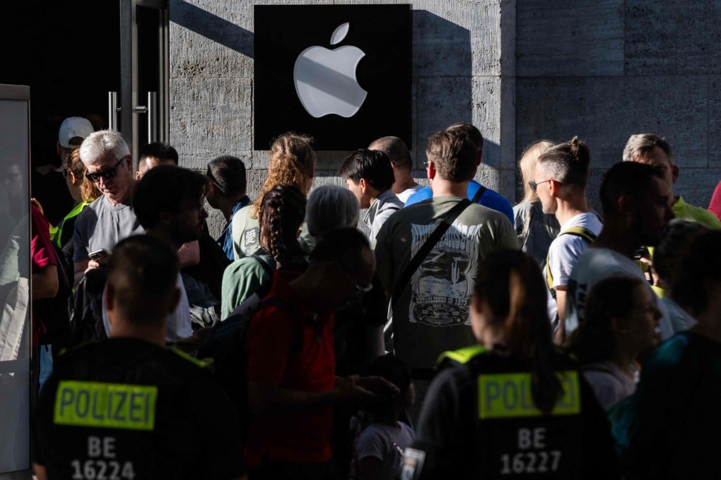 Police officers watch over customers queuing up in front of an Apple store in Berlin on Friday. Photo: AFP