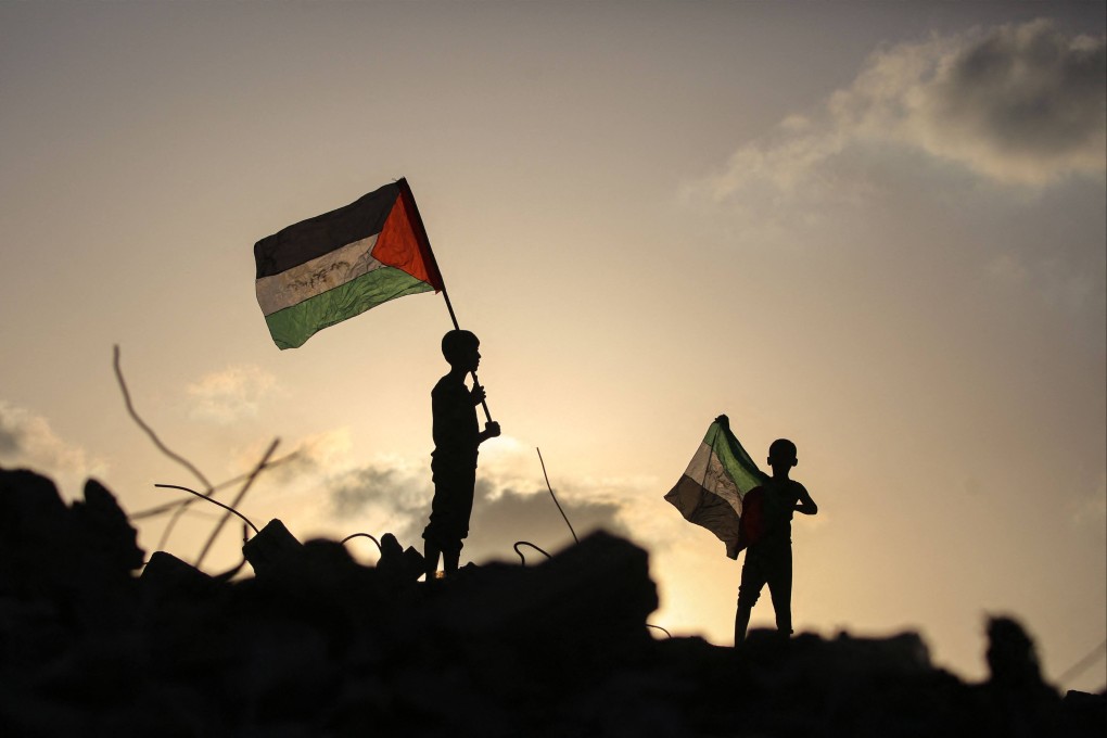 Displaced Palestinian children wave Palestinian flags as they stand among the rubble at the Bureij refugee camp in the Gaza Strip on September 22. It should be clear to the far-right government of Benjamin Netanyahu that the almost unconditional US support cannot last. Photo: AFP