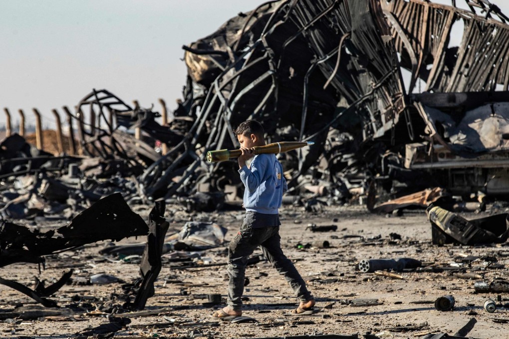 A boy carries an unexploded rocket propelled grenade at the site of an Israeli airstrike in December. Photo: AFP