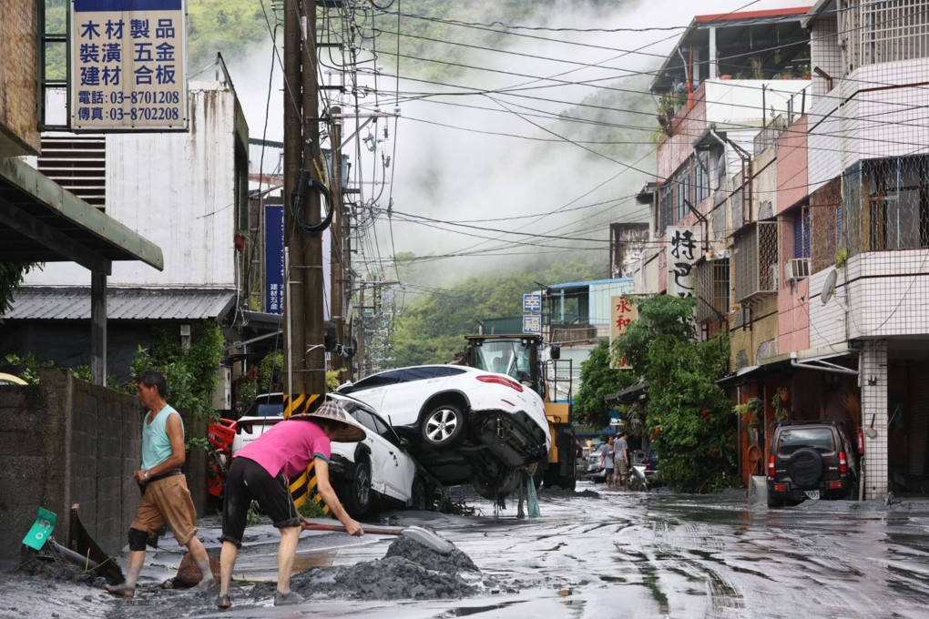 Residents clear mud from their property, while damaged cars are seen in the background, in Hualien on Wednesday after Typhoon Ragasa triggered a barrier lake to burst, flooding a township below. Photo: AFP