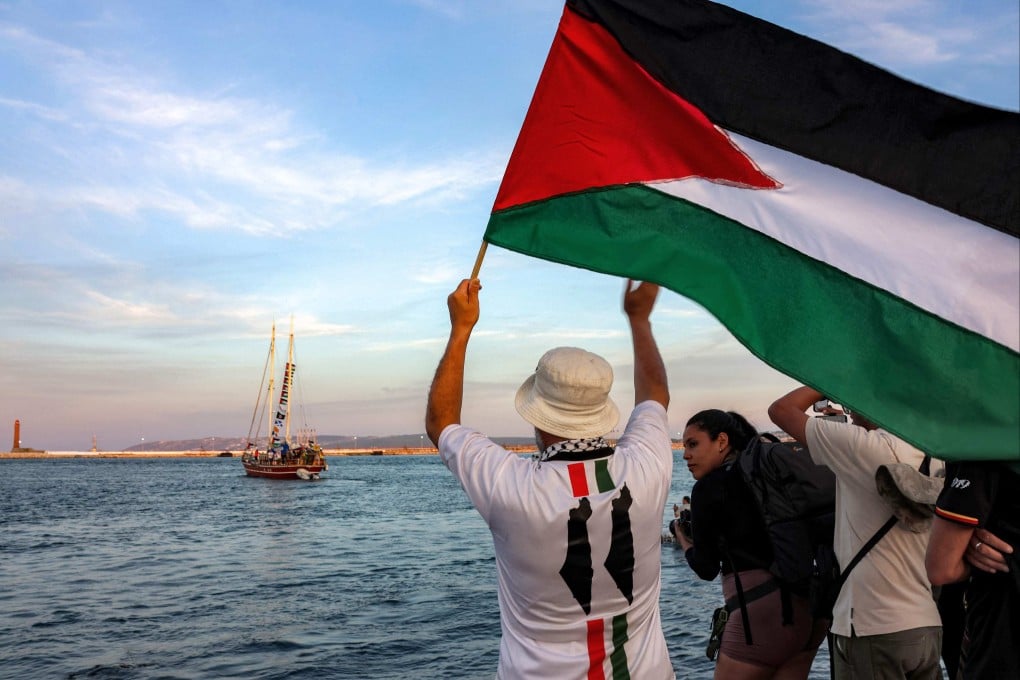 A man waves a Palestinian flag to other activists on a vessel departing from Tunisia to join the final boats participating in the Global Sumud Flotilla, headed for the Gaza Strip. Photo: AFP