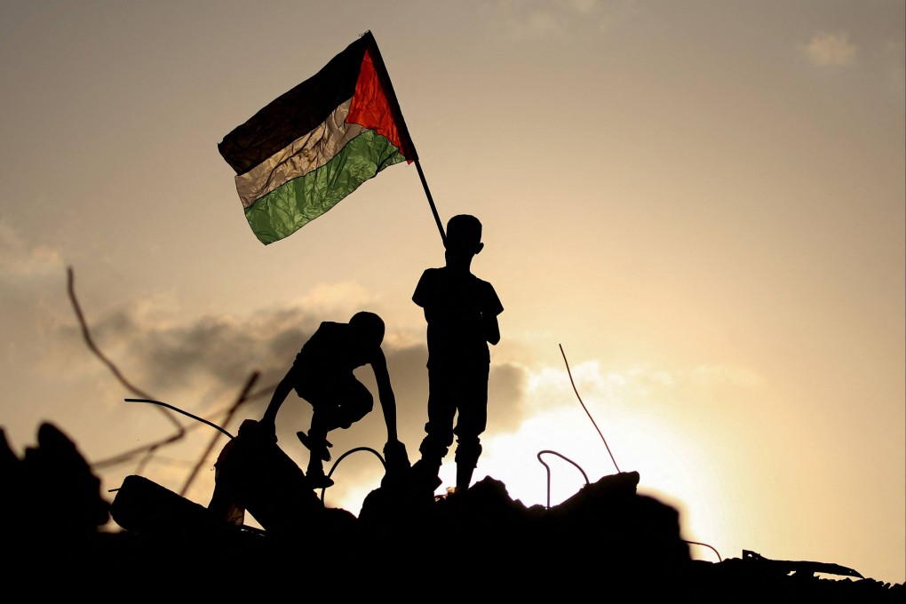 A boy waves the Palestinian flag as he stands on the rubble of a destroyed building in the central Gaza Strip on Monday. Photo: AFP