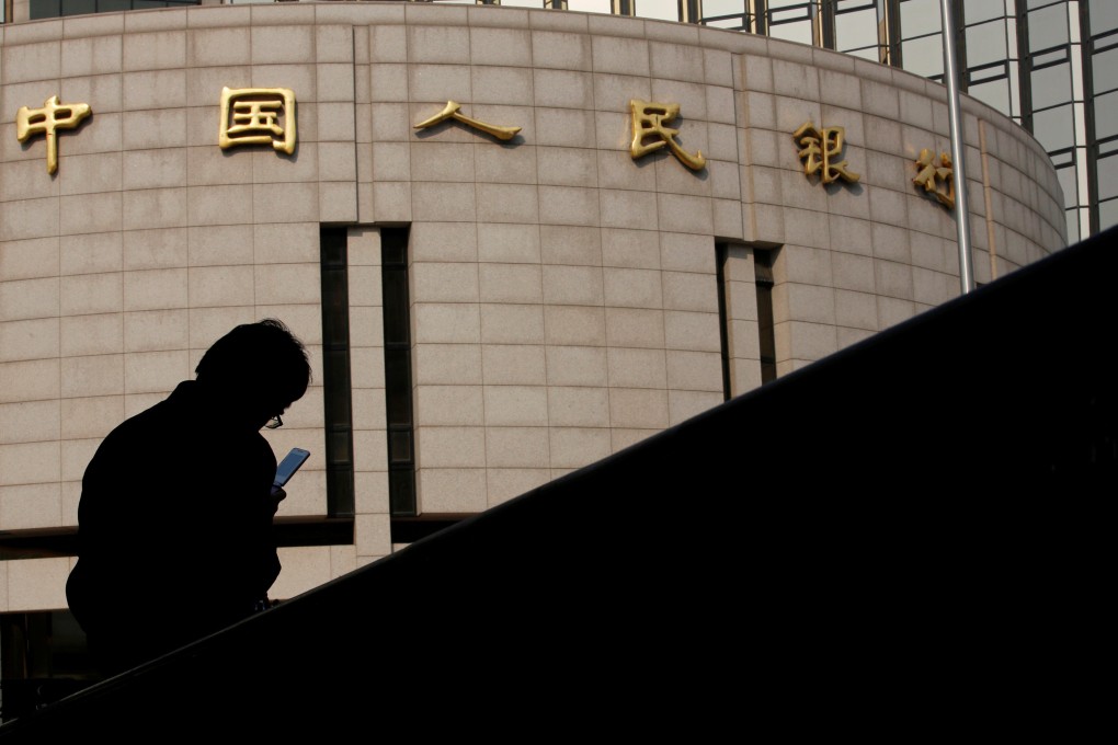 A man sits in front of the headquarters of the People’s Bank of China, the country’s central bank, in Beijing. Photo: Reuters