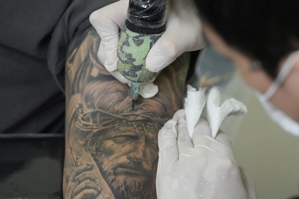 Tattoo artist Song Jaemin works to tattoo an image of Jesus Christ on the forearm of Lee Byong-joo at his studio in Goyang, South Korea. Photo: AP