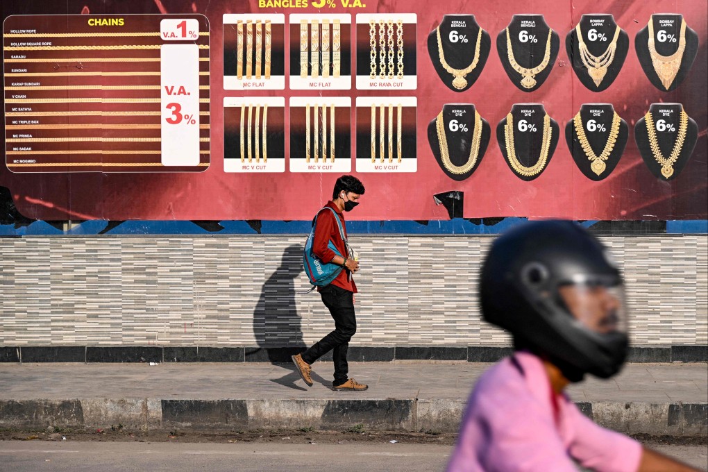 A man walks past an advertisement of gold jewellery displayed on a wall in Chennai on August 25. The disruptions caused by the US tariffs go beyond reduced output, spreading into people losing their jobs, workplaces closing and a compounding effect across supply chains and service providers. Photo: AFP
