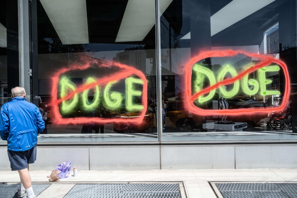 Members of the climate protest group Extinction Rebellion spray paint anti-Doge messages on the outside of a Tesla showroom in New York City. in April. Photo: AFP