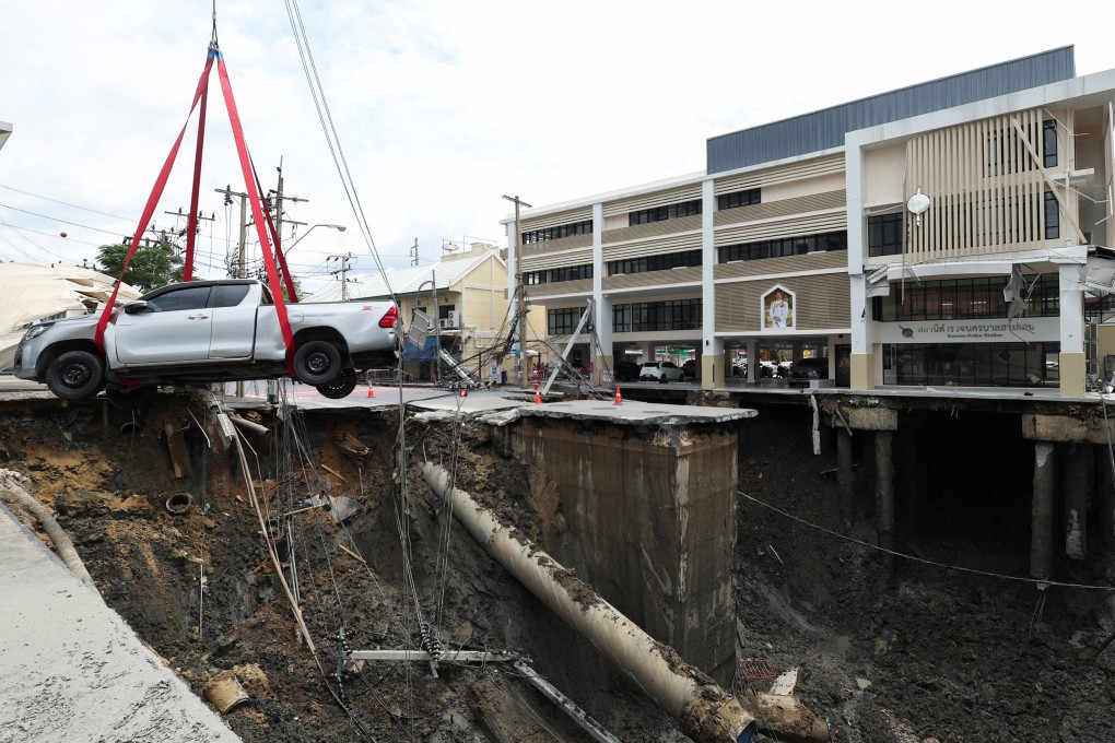 A vehicle teetering on the edge of a massive sinkhole that opened on Samsen Road in Bangkok is moved to a safe space on Wedmesday. Photo: Reuters