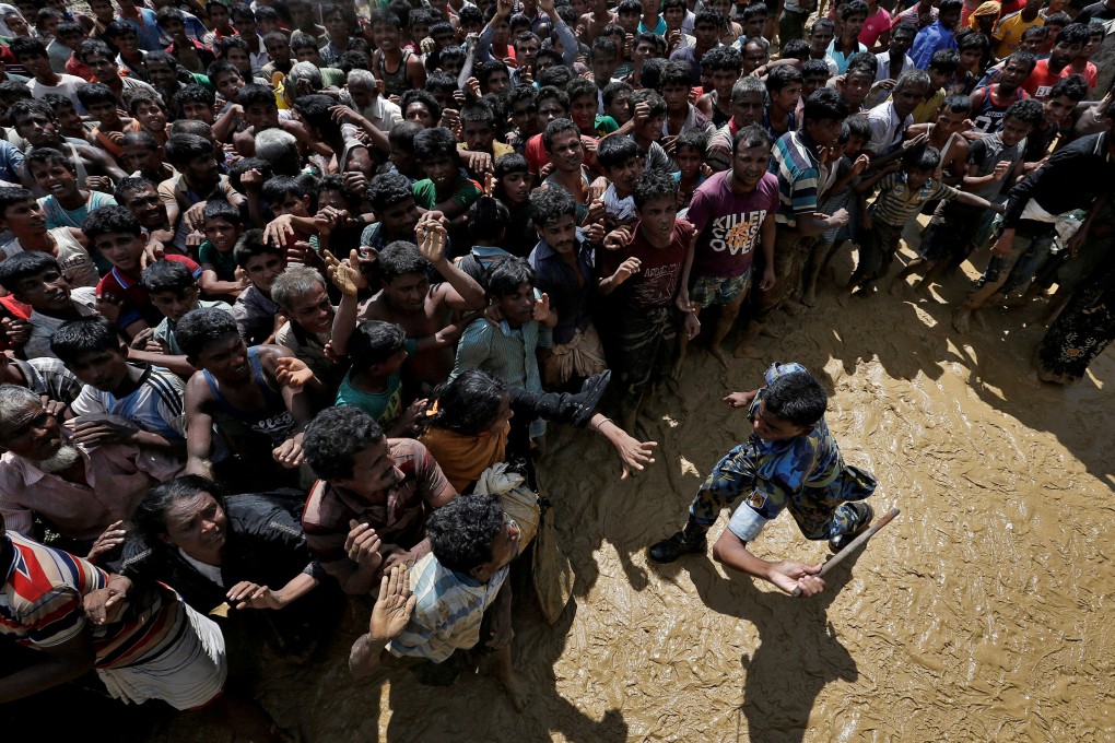A security officer attempts to control Rohingya refugees waiting to receive aid in Cox’s Bazar, Bangladesh, on September 21, 2017. The persecution of the Rohingya Muslims that year forced more than a million of them to flee and seek refuge in other countries. Photo: Reuters