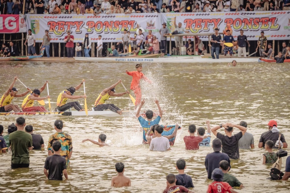 A young boy stands at the bow of a boat as spectators in the river cheer passionately for their favorite team during the 2025 Pacu Jalur Festival on August 24, in Kuantan Singingi Regency, Riau Province, Indonesia. Photo: Afrianto Silalahi