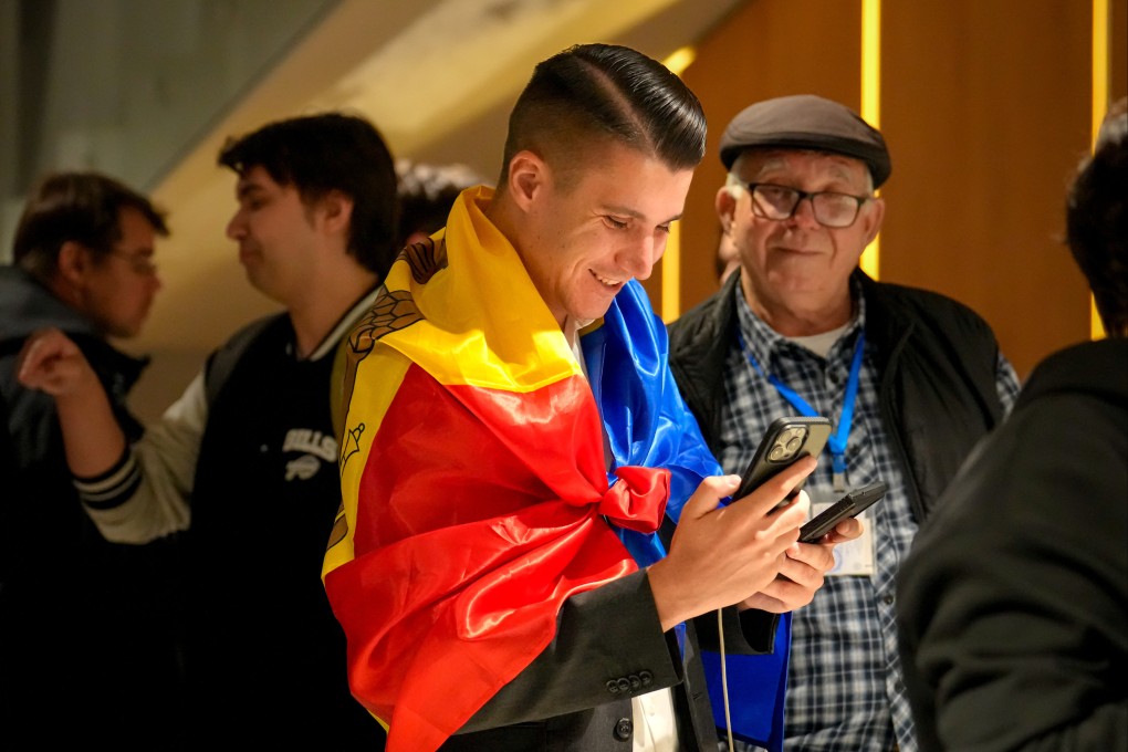 A supporter of the pro-EU Party of Action and Solidarity (PAS), draped in the Moldovan flag, smiles as he checks partial results on a phone after the polls closed for the parliamentary election, in Chisinau, Moldova on Sunday. Photo: AP