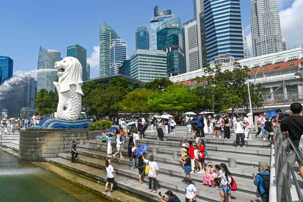 Visitors take photos by the iconic Merlion statue at Singapore’s Marina Bay waterfront. The city state’s population has reached a record 6.11 million, according to official data released in September. Photo: AFP
