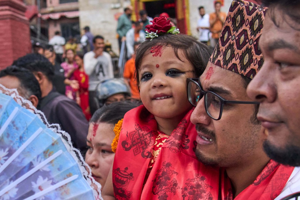 Nepal’s newly appointed living goddess, Kumari Aryatara Shakya, is carried by her father as they walk towards Kumari Ghar, the temple palace where she will be living in Kathmandu, Nepal on Tuesday. Photo: AP