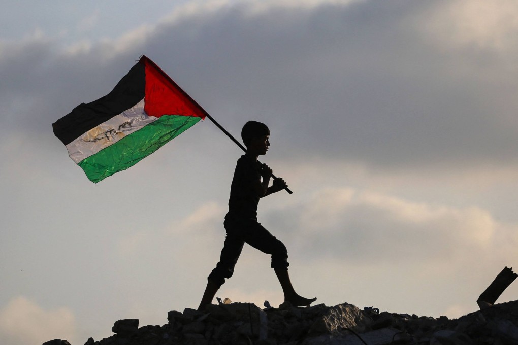 A displaced Palestinian child waves a Palestinian national flag as he walks on the rubble of a destroyed building in the central Gaza Strip on September 22. Photo: AFP