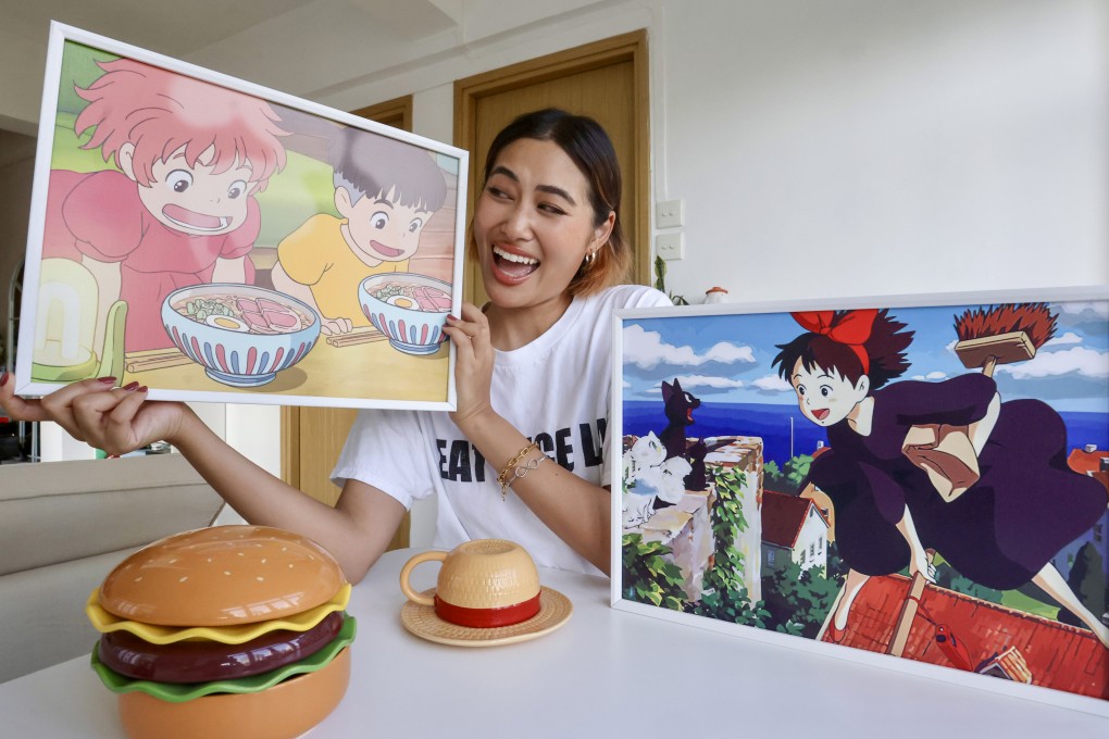 Lukian Wang holds a picture of a scene from Studio Ghibli’s 2008 anime Ponyo at her home in Tsim Sha Tsui, Hong Kong. Her first viral video was of her making instant noodles inspired by food in the film. Photo: Jonathan Wong