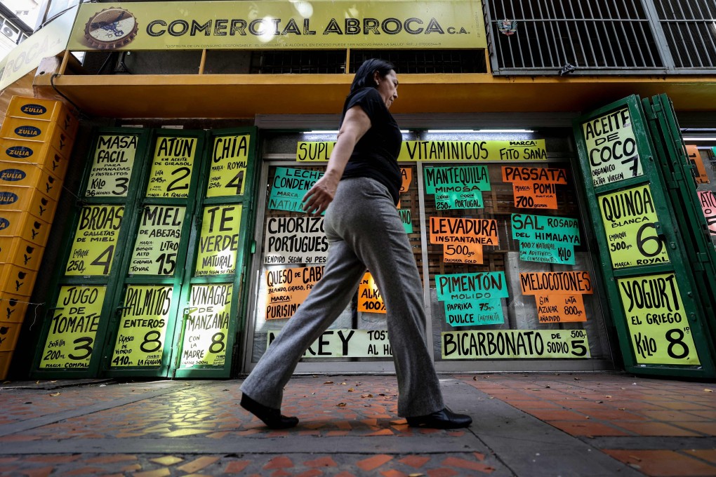 A woman walks past signs displaying prices in US dollars in Caracas, Venezuela, on June 2. Photo: AFP