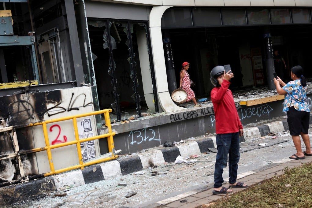People use their phones to take photos of a bus stop burned during a protest over lawmakers’ pay on August 30. Photo: Reuters