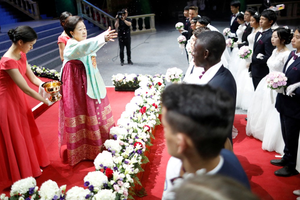 Han Hak-ja, widow of  Moon Sun-myung, sprays holy water to bless couples during a Unification Church mass wedding ceremony. Photo: Reuters