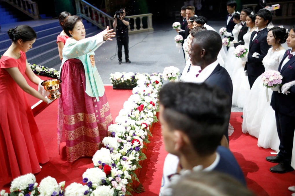 Han Hak-ja, widow of Moon Sun-myung, sprays holy water to bless couples during a Unification Church mass wedding ceremony. Photo: Reuters