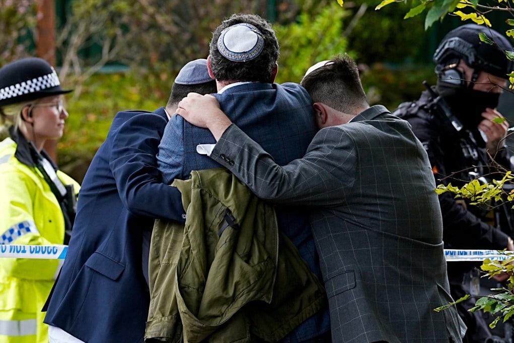 Members of the Jewish community comfort each other near to the Heaton Park Hebrew Congregation synagogue in Manchester on Thursday. Photo: PA via AP