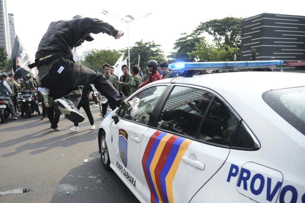 A student attacks a police car during a protest in Jakarta on August 29 following the death of a delivery rider who was run over by a police armoured vehicle in a rally against lawmakers’ privilege. Photo: AP