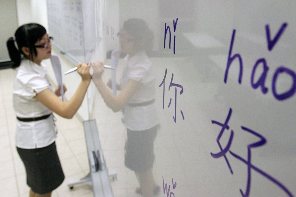 An educator writes Chinese characters on a whiteboard in Singapore. Photo: Reuters