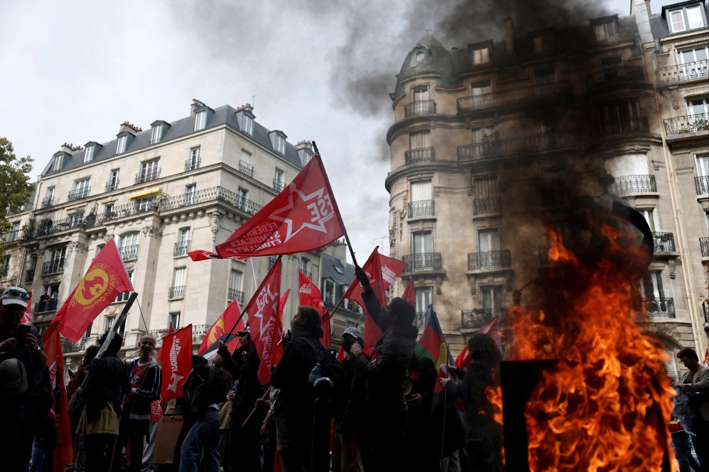 Protesters walk past a burning garbage bin during a demonstration in Paris on October 2 that was part of a day of nationwide strikes and protests against the French government’s proposed austerity measures. Photo: Reuters
