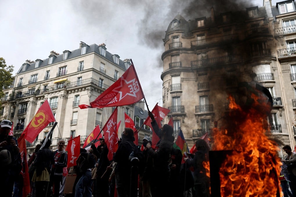 Protesters walk past a burning garbage bin during a demonstration in Paris on October 2 that was part of a day of nationwide strikes and protests against the French government’s proposed austerity measures. Photo: Reuters