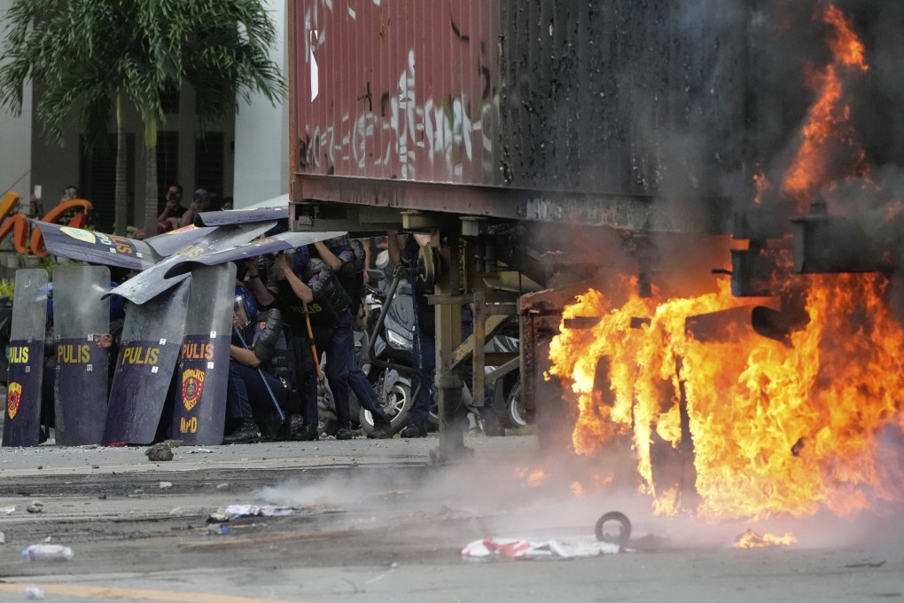 Police shield themselves beside a burning container during clashes with anti-corruption protesters in Manila on September 21. Photo: AP