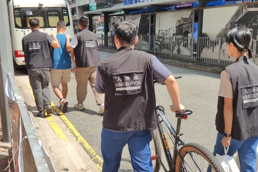 Hong Kong immigration officers detain a man suspected of working illegally as a food delivery cyclist. Photo: Handout