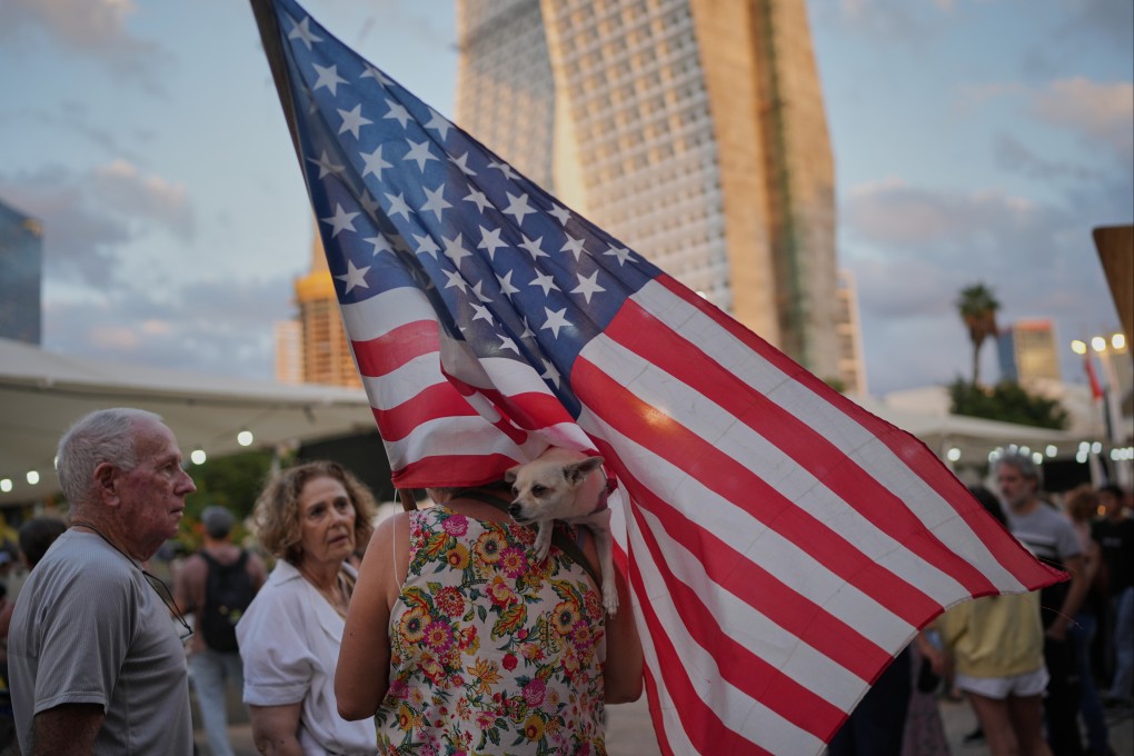 A woman carrying an American flag holds her dog in Tel Aviv, Israel, on Thursday, as people celebrate the announcement of the peace agreement. Photo: AP