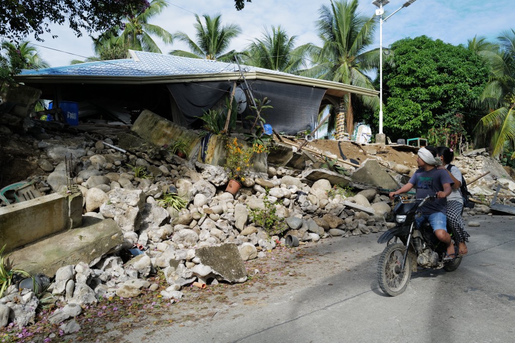 Two people on a motorcycle look at the destroyed house of Vilma Lagnayo, a resident, in Manay, Davao Oriental, following a magnitude 7.4 earthquake that hit the southern Philippines on Friday. Photo: Jeoffrey Maitem