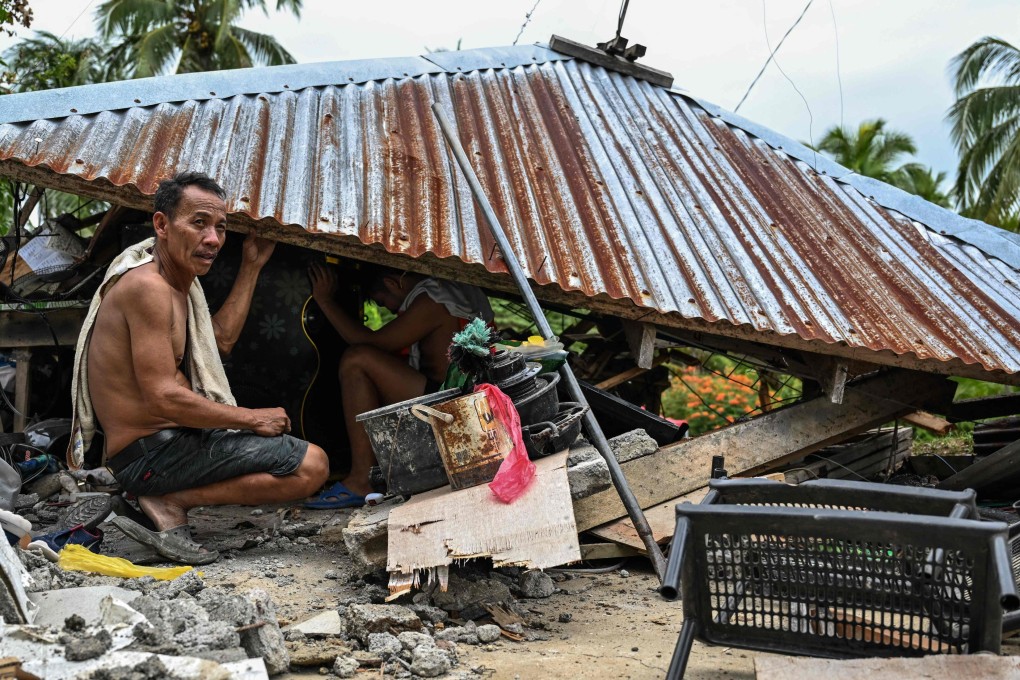 Men look for items in a collapsed house in Manay on Saturday. Photo: AFP