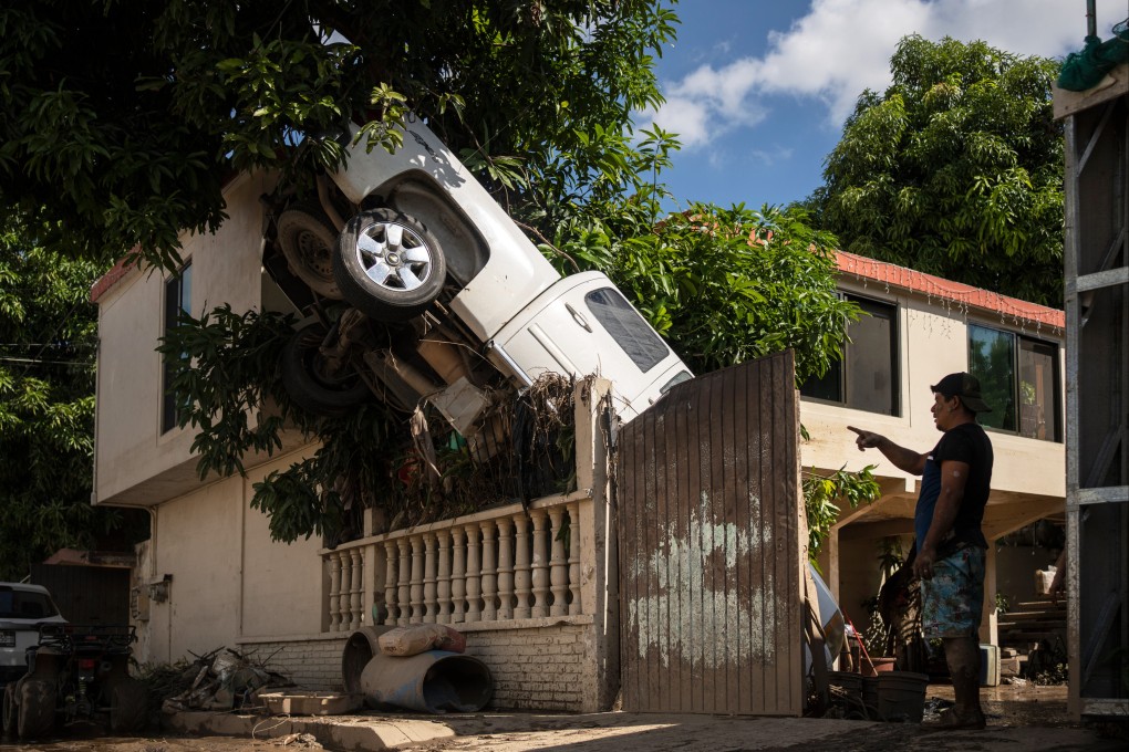 A pickup truck hangs over a fence in Poza Rica, Veracruz state, Mexico, after rain and flooding. Photo: AP