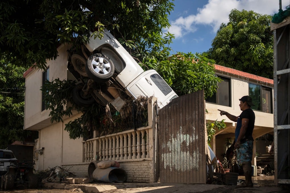 A pickup truck hangs over a fence in Poza Rica, Veracruz state, Mexico, after rain and flooding. Photo: AP
