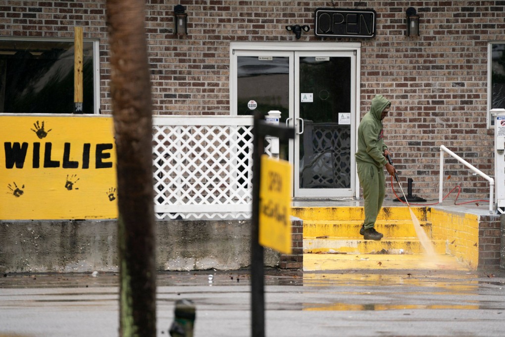 A man uses a power washer to clean blood off the front steps at Willie’s Bar and Grill. Photo: AFP