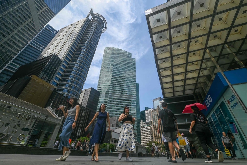People walk out for a lunch break in the Raffles Place financial business district in Singapore. The manpower ministry has said labour market adjustments will come mainly through slower hiring and moderated wage growth. Photo: AFP