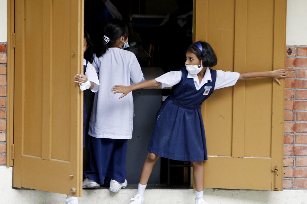 Students, wearing face masks as a precaution against swine flu, close doors to their school after it was shut following the discovery of swine flu at a Kuala Lumpur primary school in 2009. Photo: AP